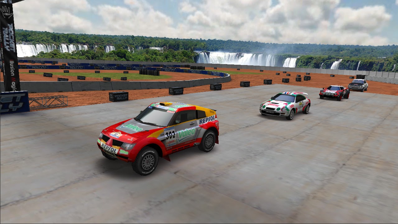 Three rally cars racing on a concrete arena with waterfalls in the distance