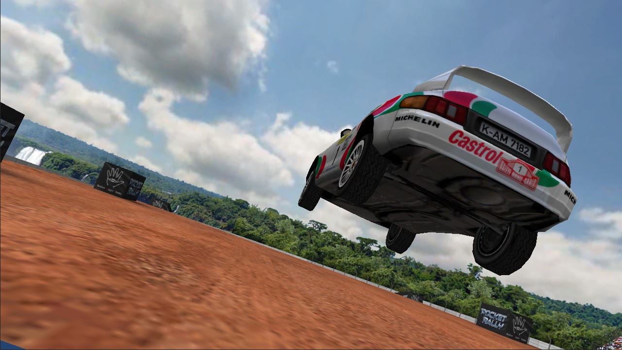 A white and green rally car mid-air over a dirt jump